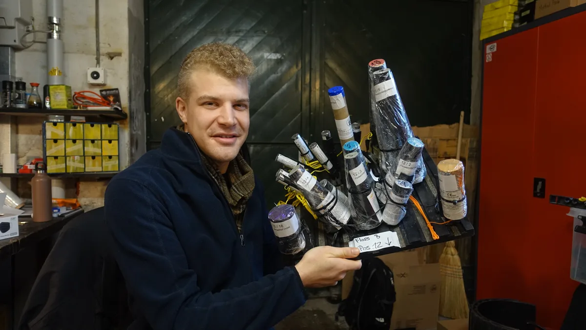 Man sieht einen jungen Mann mit Feuerwerkskörpern in den Händen. 